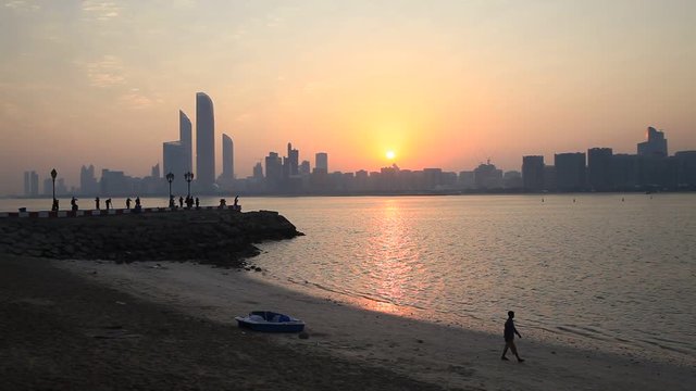 Sunrise in Abu Dhabi with silhouette of man walking by the beach