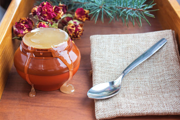 Honey in a jar on a wooden tray