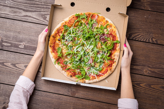 Woman Holding Pizza In Cardboard Box. Top View