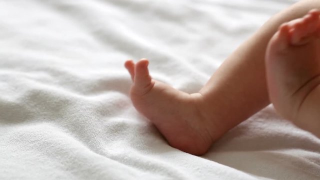 Little moving feet of lying newborn baby, closeup