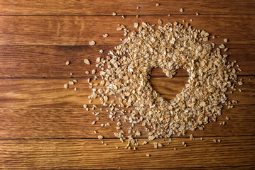 Heart painted in oatmeal on wooden background. Healthy food concept