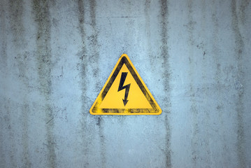 Yellow electricity warning sign on a weathered background