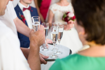 Guests take glasses of champagne from the tray standing before w