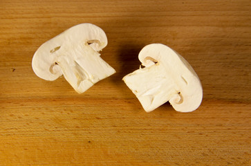 White mushroom cut in two halves on wooden board