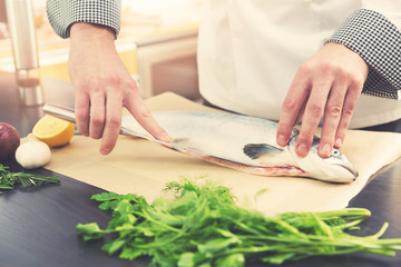 chef preparing salmon fish for cooking in kitchen