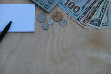 Money cash, coin, banknote, pen, notebook, calculator on wooden background with space for text