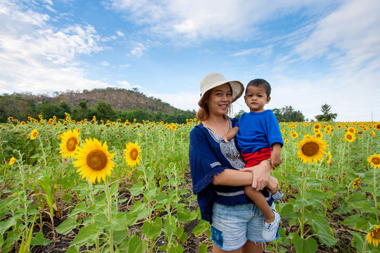 Asian Kid Or Baby Boy And Happy Young Mother In Sunflower Meadow