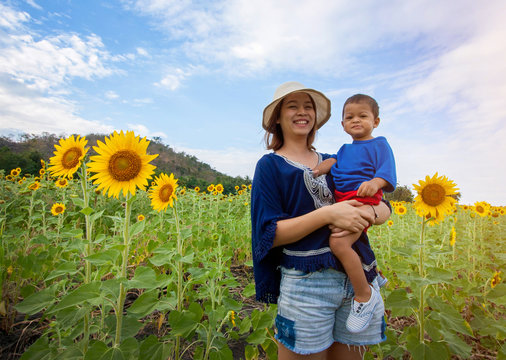 Asian Kid Or Baby Boy And Happy Young Mother In Sunflower Meadow