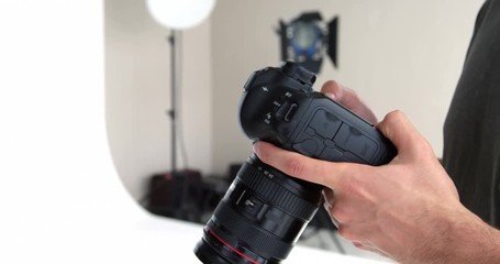 Mid-section of photographer looking at photos on digital camera in studio 4k - Powered by Adobe