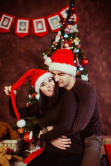 Young happy couple wearing santa's hats at studio