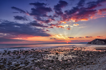 Amazing sea sunset with sun rays and water reflection