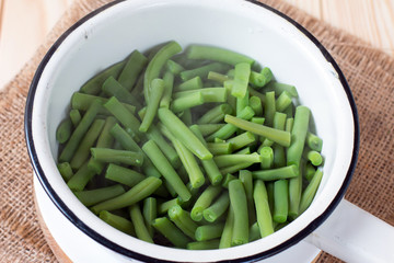 Colander with raw green bean on the cutting board