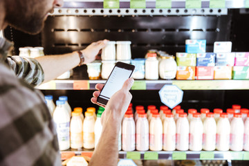 Man using mobile phone on shopping at grocery shop
