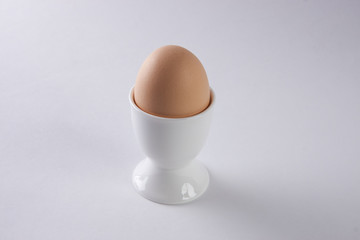Brown egg in egg cup on white background