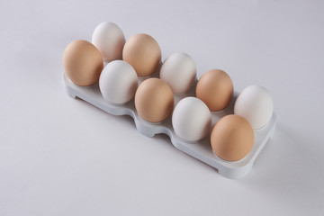 Egg tray with white and brown eggs on white background