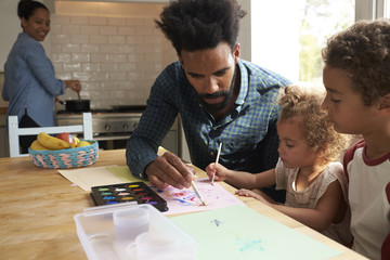 Naklejka premium Children And Father Painting Picture On Kitchen Table
