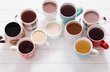 Many cups of  hot drinks on white wooden table
