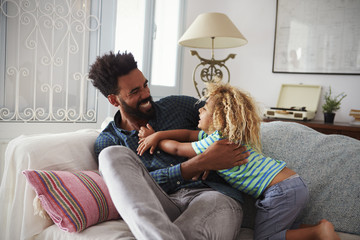 Father And Son Playing Game On Sofa Together