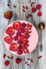 Pink acai, maca powder smoothie bowl  topped with sliced strawberries, raspberries and goji...