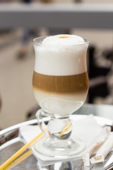 Layers of latte coffe in glass cup on table of cafe