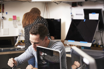 A young man and woman working on computers in a technology lab or repair shop.