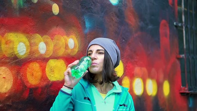 Hipster woman drinking water from a bottle, steadycam shot, slow motion shot at 240fps
