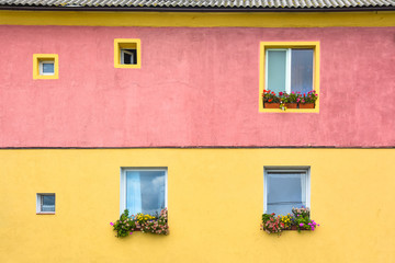 Fototapeta na wymiar Bright multi-colored house wall, flowers are on the windows