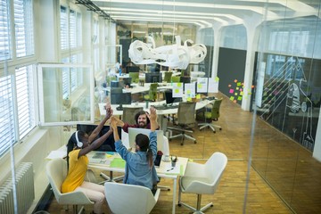 Team of business executives giving high five at desk