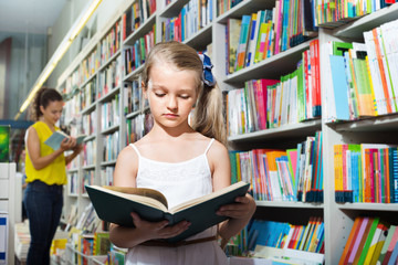 Small girl in school age standing with open book
