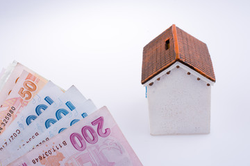 Turkish Lira banknotes by the side of a model house