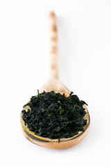 Dried japanese wakame seaweed in wooden spoon, isolated on white background
