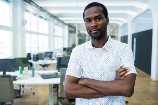 Graphic designer standing with arms crossed in office