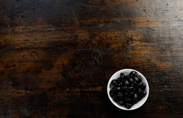 Bowl of cured black olives on rustic wood