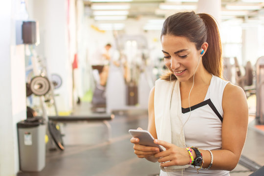 Athletic girl using smartphone in fitness gym.