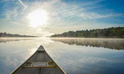 Canoe trip in the morning.  Brilliant and bright mid-summer sunshine morning, paddling a canoe in the middle of quiet, calm and peaceful Corry lake. - 134748119