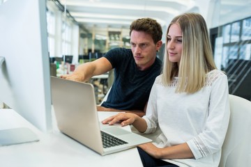 Graphic designers working over laptop at desk