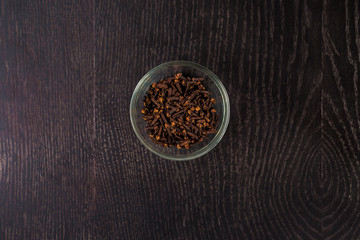 dried clove in a glass bowl - top view. On  black background.