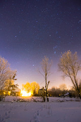Sky full of stars above snowy winter village landscape