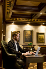 Young man working on a laptop in the room with antique furniture