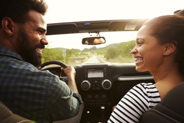 Happy couple driving in their car looking at each other