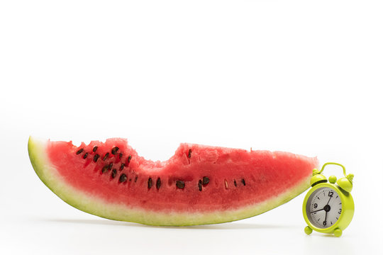 bitten off red watermelon and alarm clock isolated on white