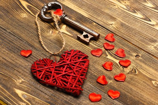 red heart and metallic key on wood as valentines decoration