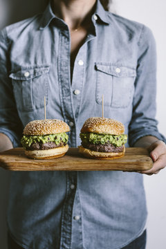 A woman is photographed from the front view while holding two gu