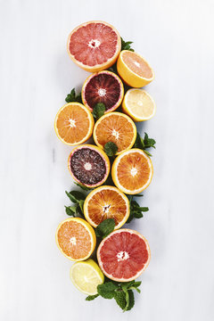 Halved oranges, grapefruits and mint display on marble