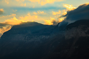 Naklejka na ściany i meble Sunlight breaking through the clouds over a mountain