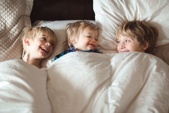 Happy kids lying under duvet