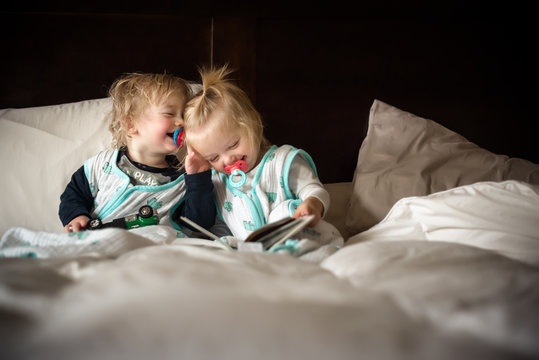 Twins laughing on bed 
