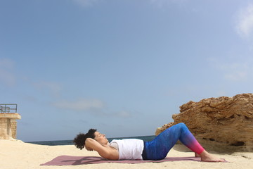 Fototapeta na wymiar Mujer haciendo abdominales en la playa, chica entrenando al aire libre