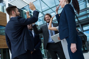 Group of happy businesspeople giving high five to each other