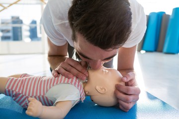 Paramedic practising resuscitation mouth to mouth on dummy
